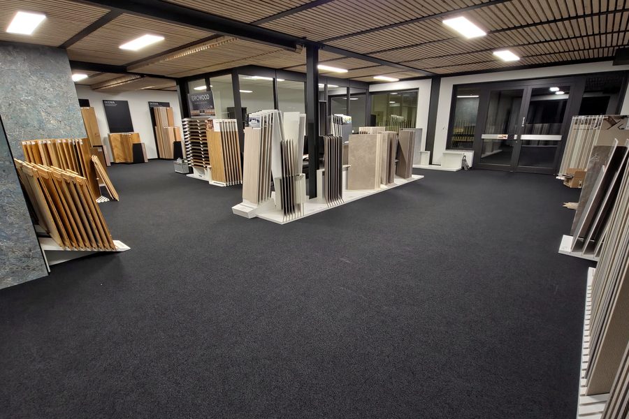 Interno dello showroom con espositori di pavimenti e rivestimenti e pavimento in moquette scura