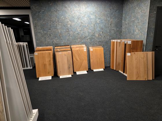 Campioni di pavimenti in legno appoggiati davanti a una parete rivestita con grandi lastre effetto pietra